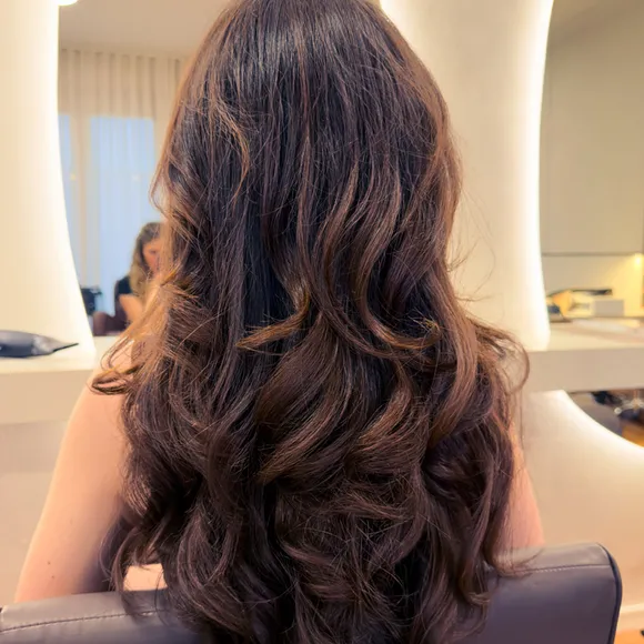 Back view of long brunette hair styled in voluminous, bouncy curls