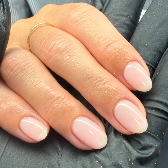Close up of short almond nails in a sheer milky pink